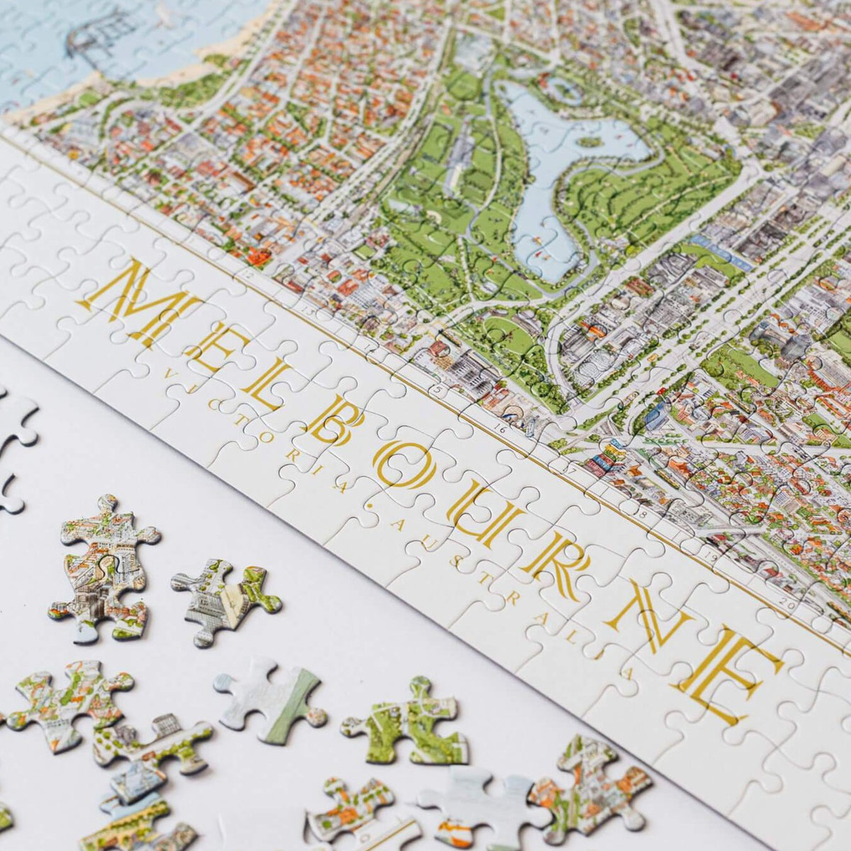 The Melbourne Map 1,000-piece jigsaw puzzle on a white board. The image shows the completed puzzle on a diagonal and some loose piece next to it.