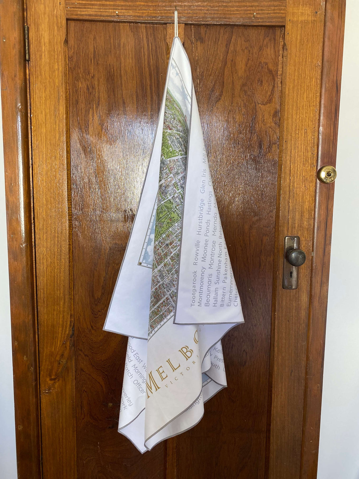 The Melbourne Map Beach Towel hanging on the back of a door using the handy hang tag that is sewn into the border. 