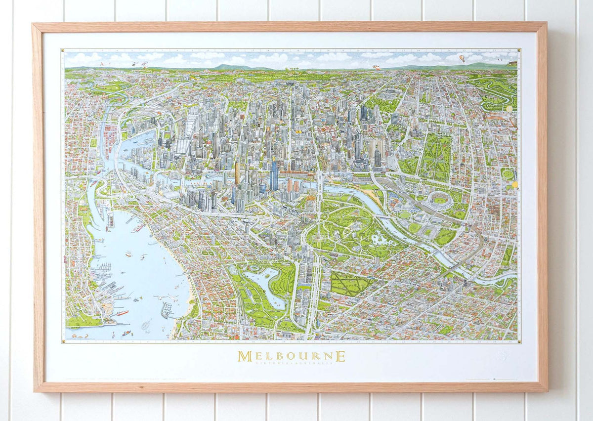 A large version of The Melbourne Map colour open edition art print in an oak frame hanging on a white panelled wall in a bright airy room