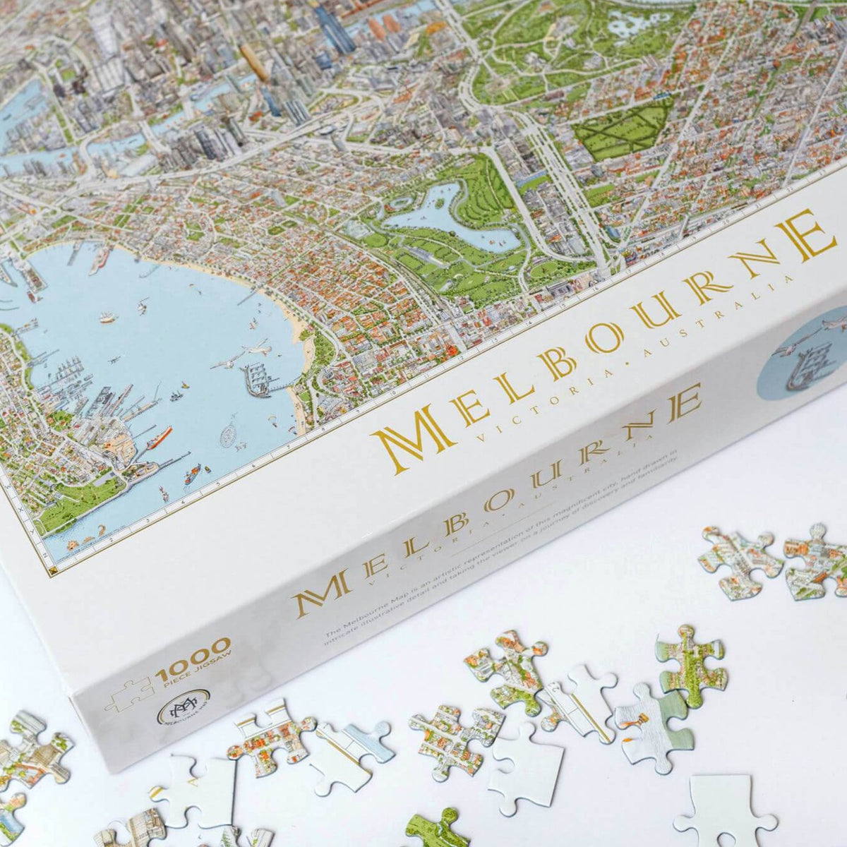 The Melbourne Map 1,000-piece jigsaw puzzle on a white table showing the bottom left corner of the box and some loose pieces