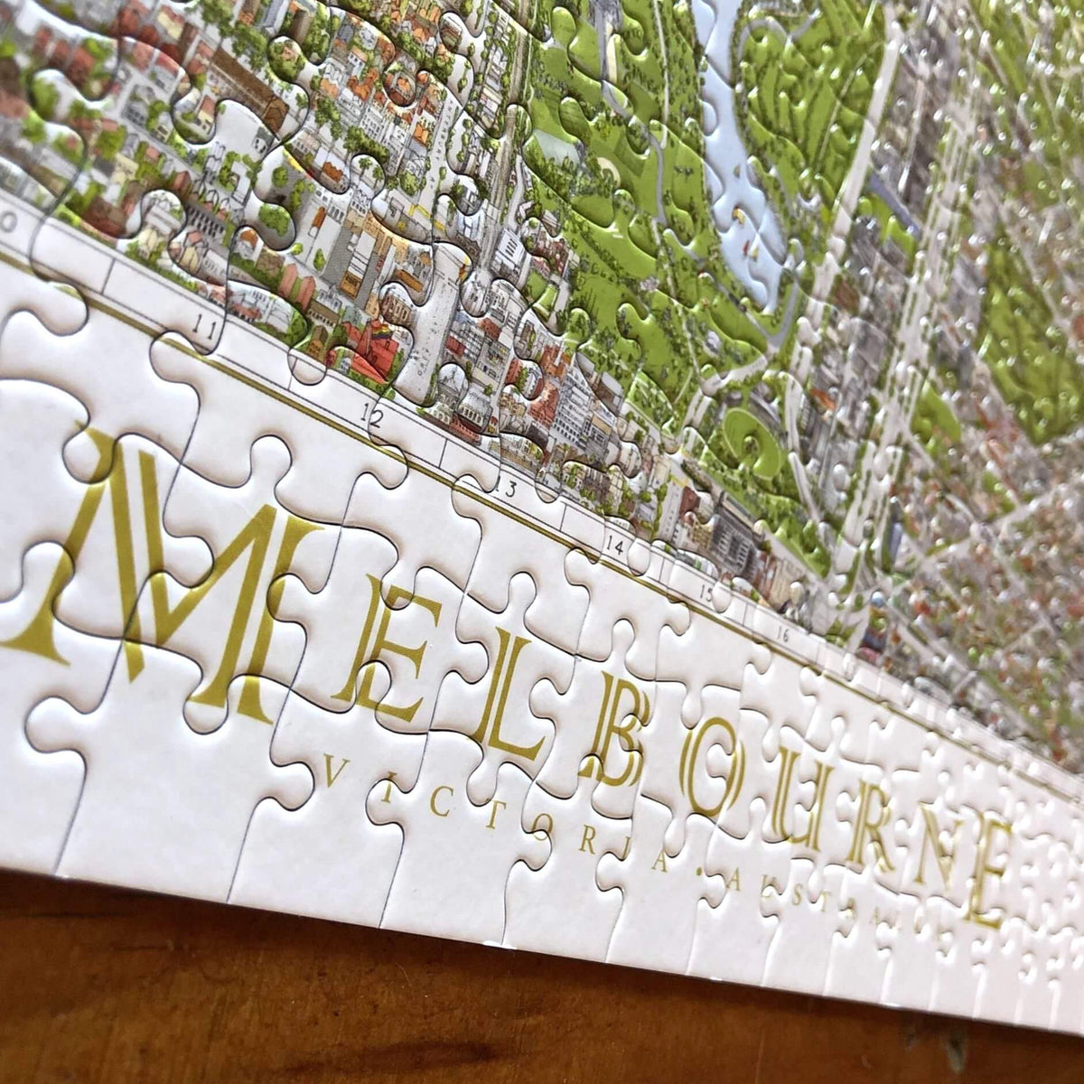 The Melbourne Map 1,000-piece jigsaw puzzle completed on a natural timber table. Close-up of the &quot;Melbourne&quot; pieces