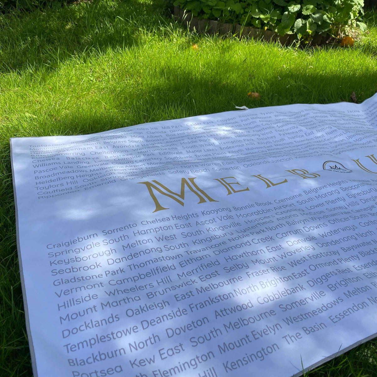 The Melbourne Map Beach Towel being used as a picnic rug. Reverse side up showing the 398 suburbs of Melbourne 